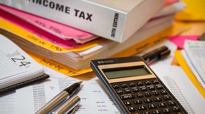 Calculating numbers for income tax return with pen, files, books and calculator