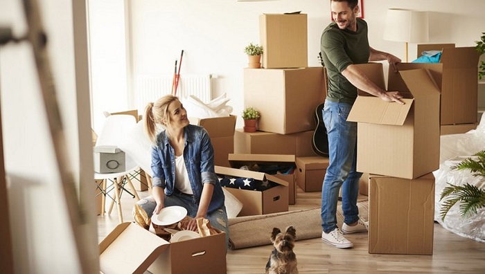 Image That Shows A Young Family Unpacking At New House with Boxes.