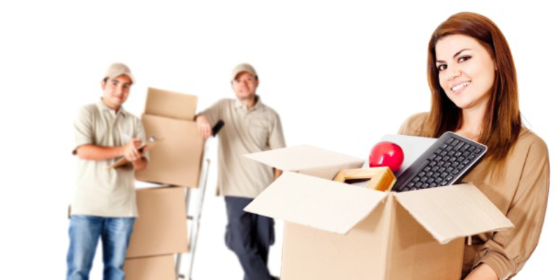 A Woman With Box Full Of Relocation Stuffs & Packers Standing On The Background.