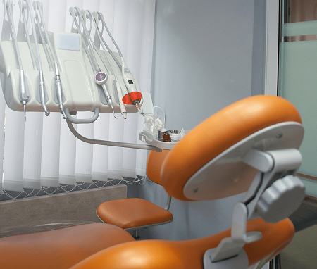 A organe dental chair,dental pen probes and otherdental eqipments plcced near the window with white shades.