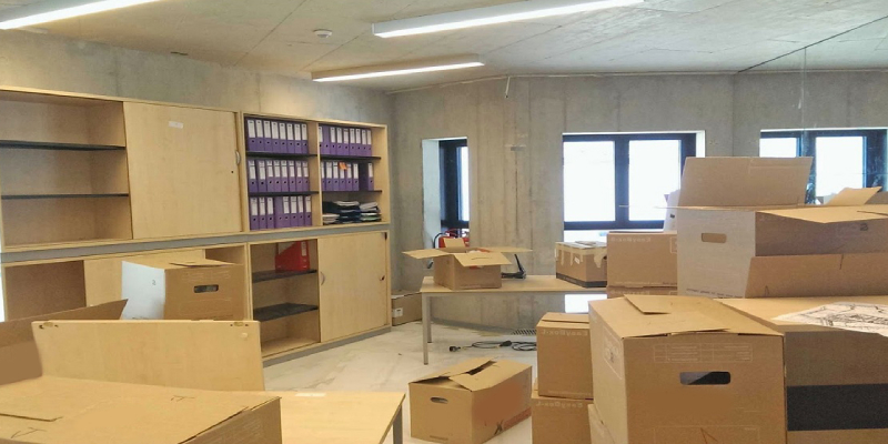 An office space in the process of shifting, with lots of packed and unpacked carton boxes.